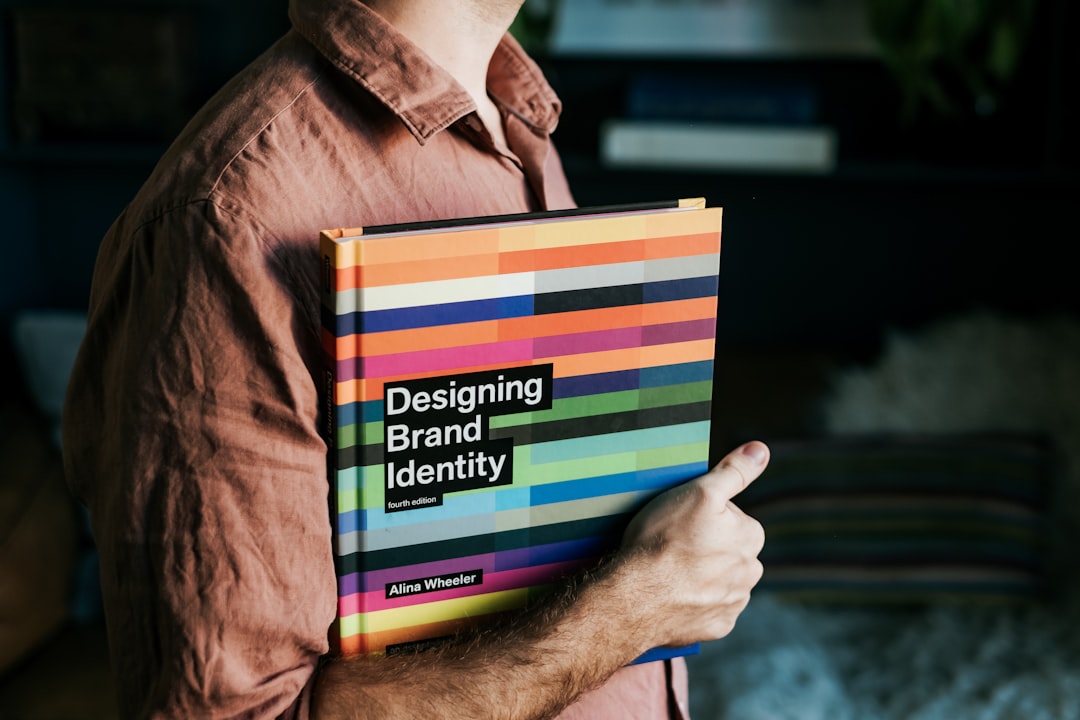 services-01 a-man-holding-a-book-that-says-designing-brand-identity-wkw5nxoxizq